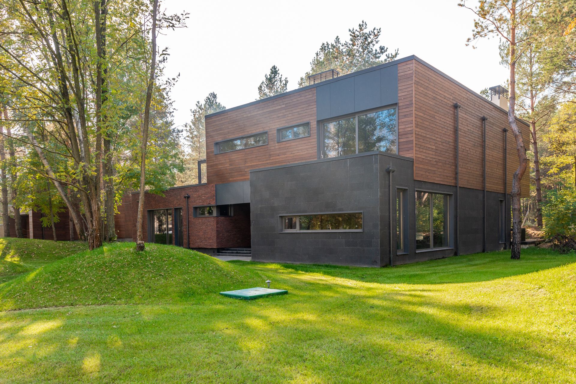 Moderne hus med trekledning, store vinduer og en frodig hage